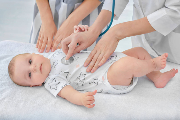 Doctor examining baby with stethoscope at home - Zdjęcie, obraz