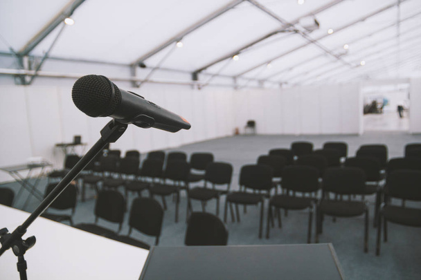 Μαύρο μικρόφωνο στην αίθουσα συνεδρίων - άδειες καρέκλες σε φόντο - Φωτογραφία, εικόνα