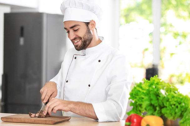 Young male chef cutting meat - Zdjęcie, obraz