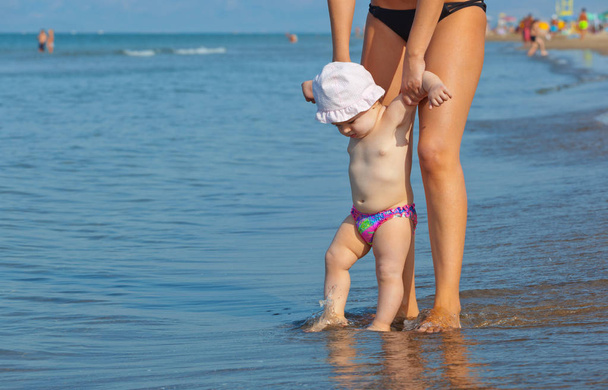 Maman apprend à sa fille à marcher jusqu'à la plage
. - Photo, image