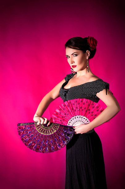 Flamenco Carmen beautiful woman in black dress with a red rose in her hair on dark background. Argentine tango or flamenco concept - Photo, image