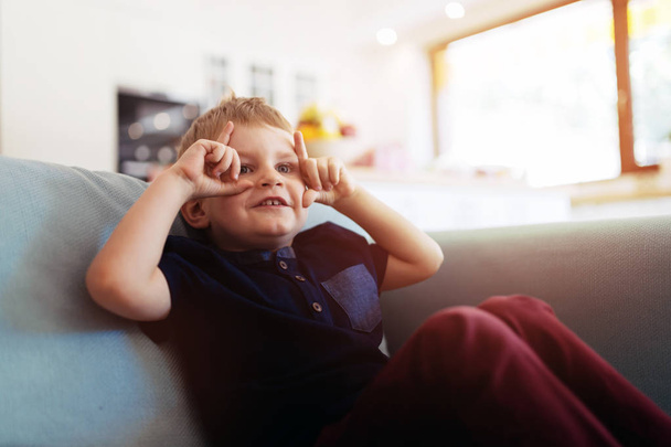 Happy boy sitting on living room couch - Photo, Image