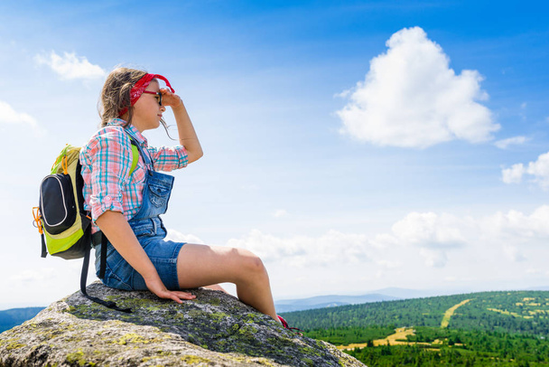 Mladá cestování dívka sedící na skále hory s batohem, re - Fotografie, Obrázek