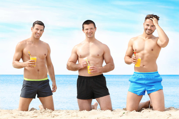 Handsome young men with drinks on sea beach - Foto, immagini
