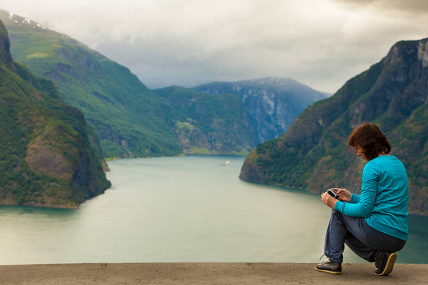 Female tourist taking photo at norwegian fjord - Foto, afbeelding