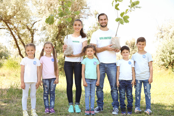 Jonge vrijwilligers en kinderen gaan bomen te planten in het park - Foto, afbeelding