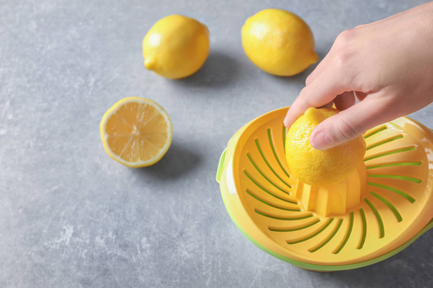 Man's hand juicing lemon with plastic squeezer  - Foto, imagen