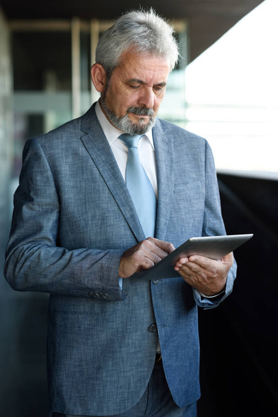Hombre de negocios sénior con Tablet PC fuera de la oficina moderna
 - Foto, Imagen