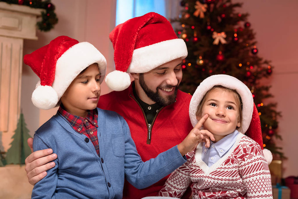 father and kids in santa hats - Фото, изображение