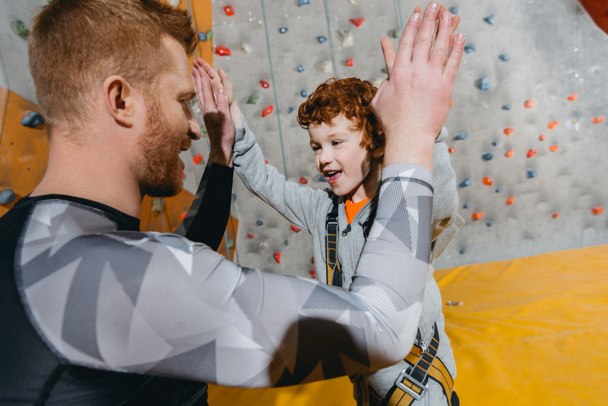 Boy in climbing harness high-fiving dad - Photo, Image