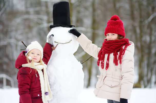 Two little girls with snowman - Valokuva, kuva