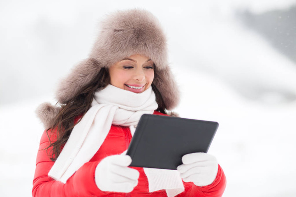 woman in winter fur hat with tablet pc outdoors - Photo, Image
