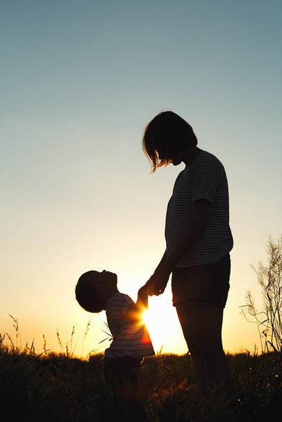 Silhouette of a woman with her child at sunset. - Photo, Image