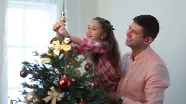 Cute girl putting decorative star on xmas tree top - Πλάνα, βίντεο
