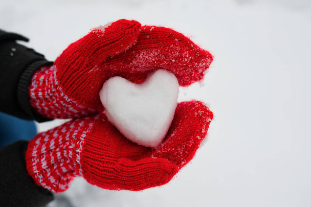 punaiset naishanskat pitävät valkoista sydäntä lumesta
 - Valokuva, kuva