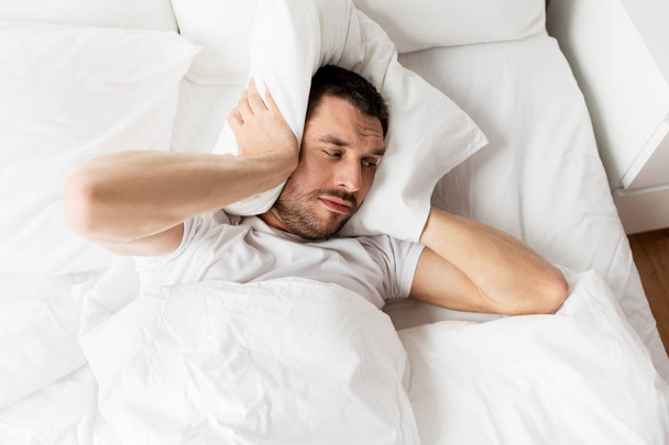 man in bed with pillow suffering from noise - Photo, image
