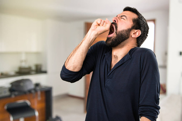 Красавчик с бородой зевает в доме
 - Фото, изображение