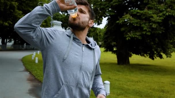 Fitness-Mann trinkt Wasser aus Flasche Spritzwasser. - Filmmaterial, Video