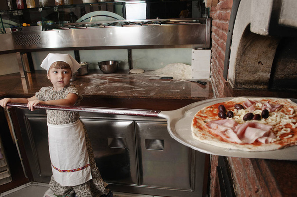 赤ちゃんのパン屋は、薪ストーブにピザを置く - 写真・画像