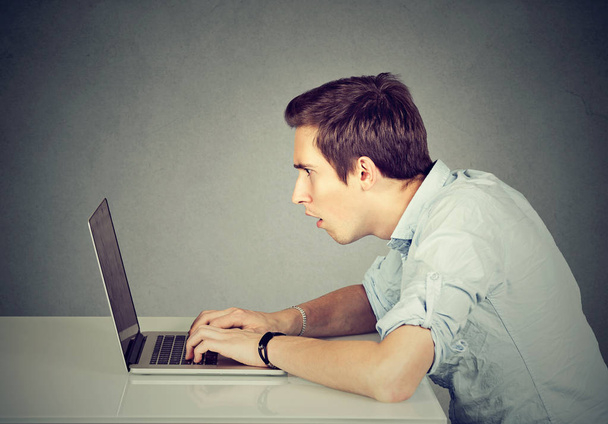 Shocked perplexed man sitting in front of laptop computer looking at screen  - Foto, Bild