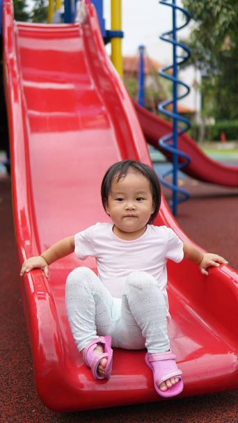 Asiatisch chinesisches Kind rutscht auf Spielplatz ab - Foto, Bild