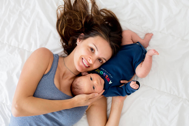 Mother and baby boy, lying in bed, hugging with love - Foto, Bild