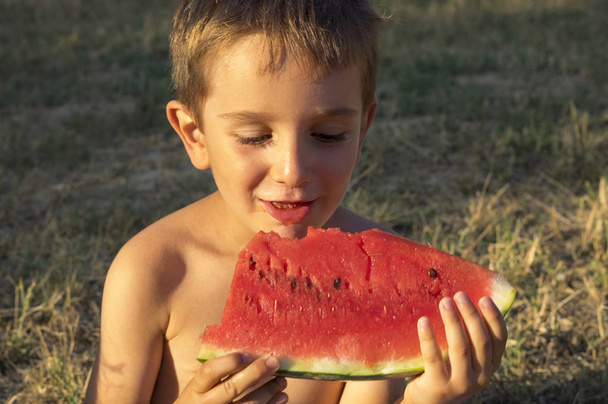 Kaukasische jongen met zijn halve eter watermeloen - Foto, afbeelding