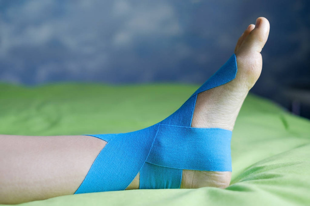 Эластичная терапевтическая синяя лента, нанесенная на левую ногу
. - Фото, изображение