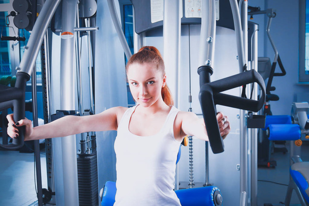 Beautiful girl at the gym exercising on trainers. Beautiful girl - Valokuva, kuva