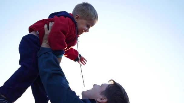 Медленное движение. Молодой отец подбрасывает своего смеющегося ребенка в воздух. Открытый отдых на природе
 - Кадры, видео
