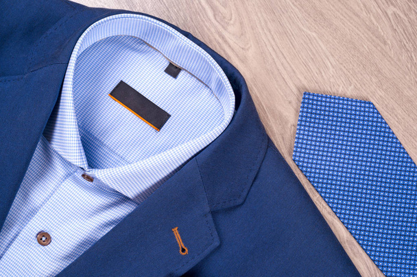 conjunto de ropa clásica para hombre - traje azul, camisas, zapatos marrones, cinturón y corbata sobre fondo de madera. - Foto, Imagen