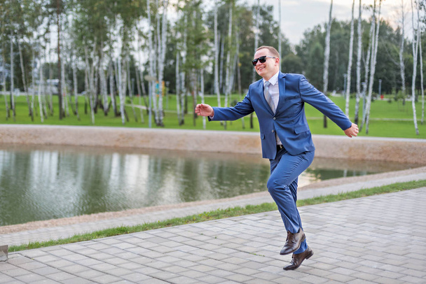 a young businessman in blue suit running jumping on the street - 写真・画像