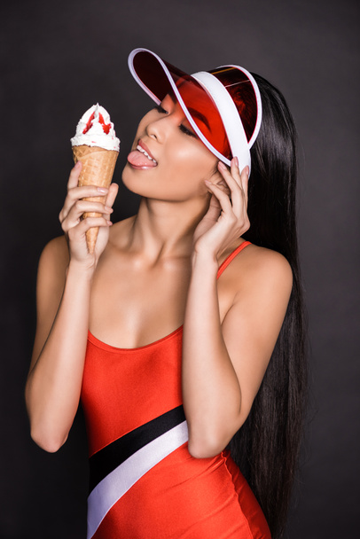 vrouw in badpak en visor likken van consumptie-ijs - Foto, afbeelding
