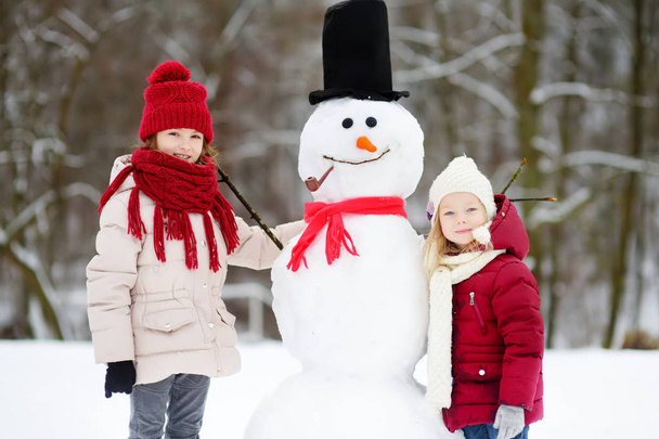Two little girls making snowman - Foto, imagen