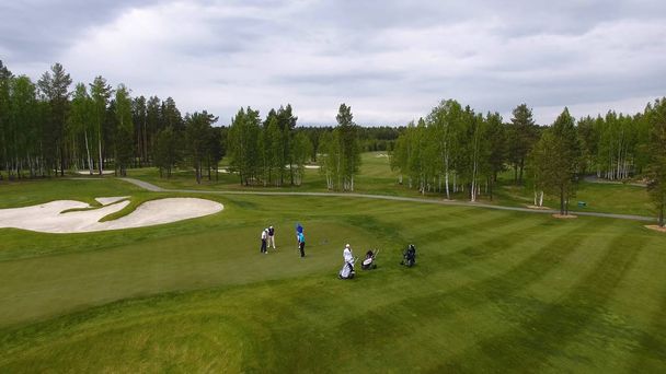 Golfers hitting golf shot with club on course while on summer vacation, aerial - Fotó, kép