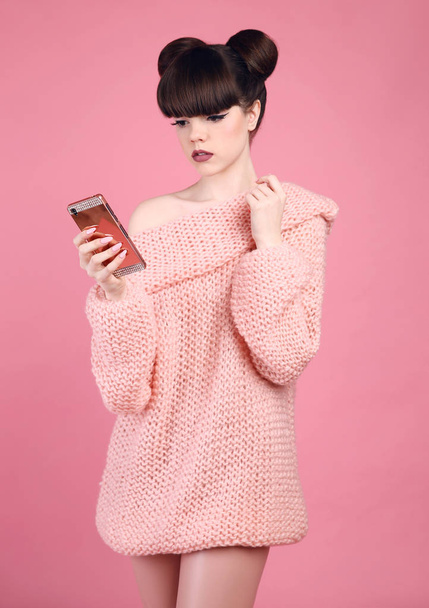 Brunetka, trzymając telefon komórkowy. Fashion studio spojrzenie nastolatków styl  - Zdjęcie, obraz