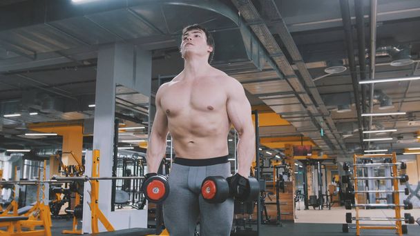 Спортсмен поднимает гантели без рубашки в спортзале
 - Фото, изображение