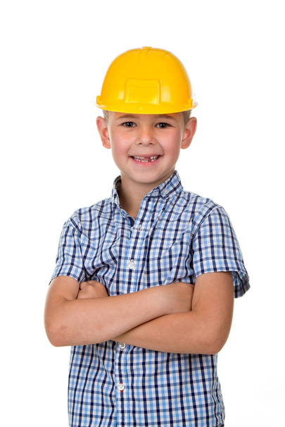 Handsome boy in blue checkered shirt and yellow building helmet, smiling on white background - Fotó, kép
