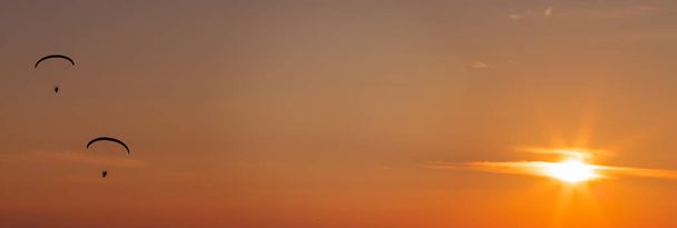 夕暮れ空飛ぶパラグライダー - 写真・画像