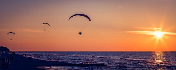 Gleitschirme fliegen bei Sonnenuntergang - Foto, Bild