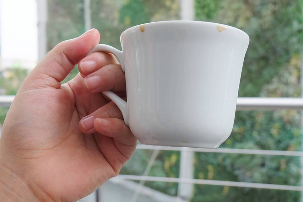 Hand met leeg kopje koffie op tafel - Foto, afbeelding