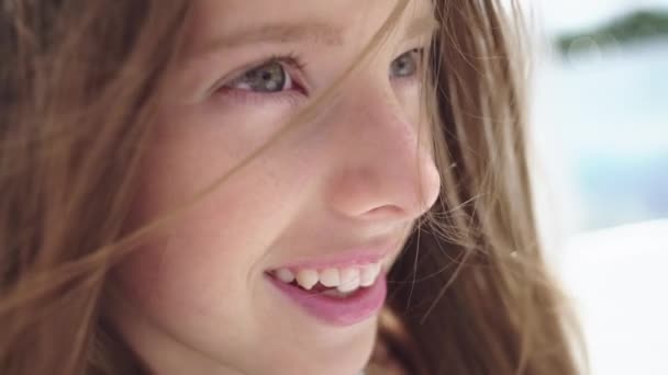 Emotional portrait of a fashionable teenage girl in the background of a summer beach and water. A beautiful smile, eyes and hair blow the wind. - Filmati, video