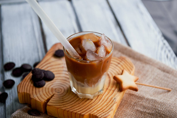 The Hong Kong iced coffee in a glass, with a straw. interesting wooden background - Fotoğraf, Görsel