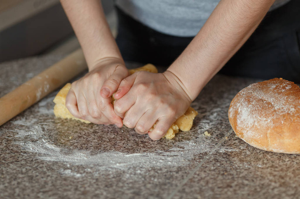 Girl's hands kneading dough in flour on table - Photo, Image