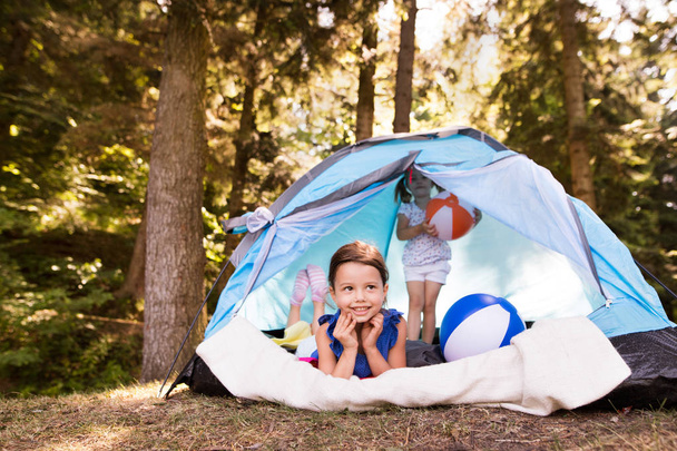 Beautiful little girls in tent camping by the lake. - Valokuva, kuva