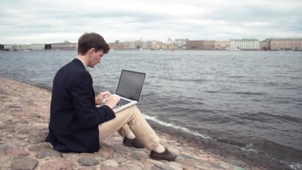 Freelancer usando laptop sentado no banco perto da beira-mar. Dia de verão
 - Filmagem, Vídeo