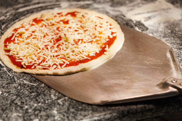 Tomar pizza cruda con pala de metal para hornear
 - Foto, Imagen