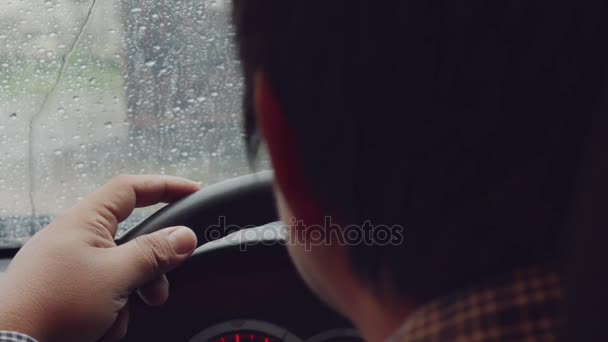 男の車の中心のステアリング ホイールに手します。指をノック激しい雨. - 映像、動画