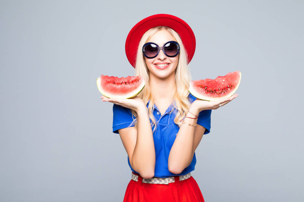 Snijd van de goedheid van de zomer. Mooie jonge vrouw houden segment van watermeloen en glimlachen terwijl staande geïsoleerd op grijs - Foto, afbeelding