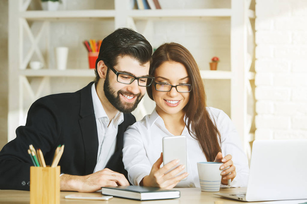 Smiling businessman and woman using smartphone  - Фото, изображение